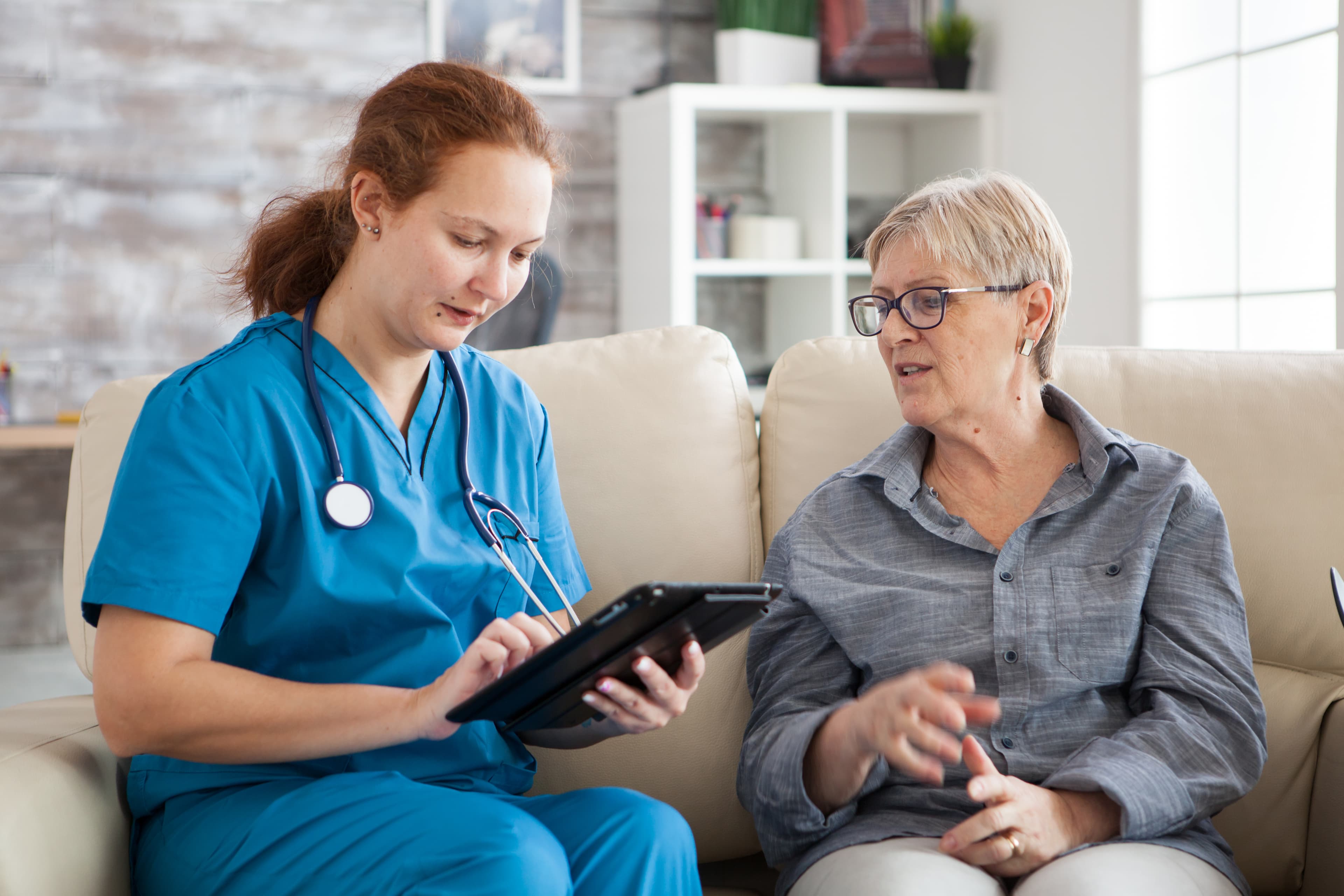 Nurse reviewing participant care plan on tablet with senior woman