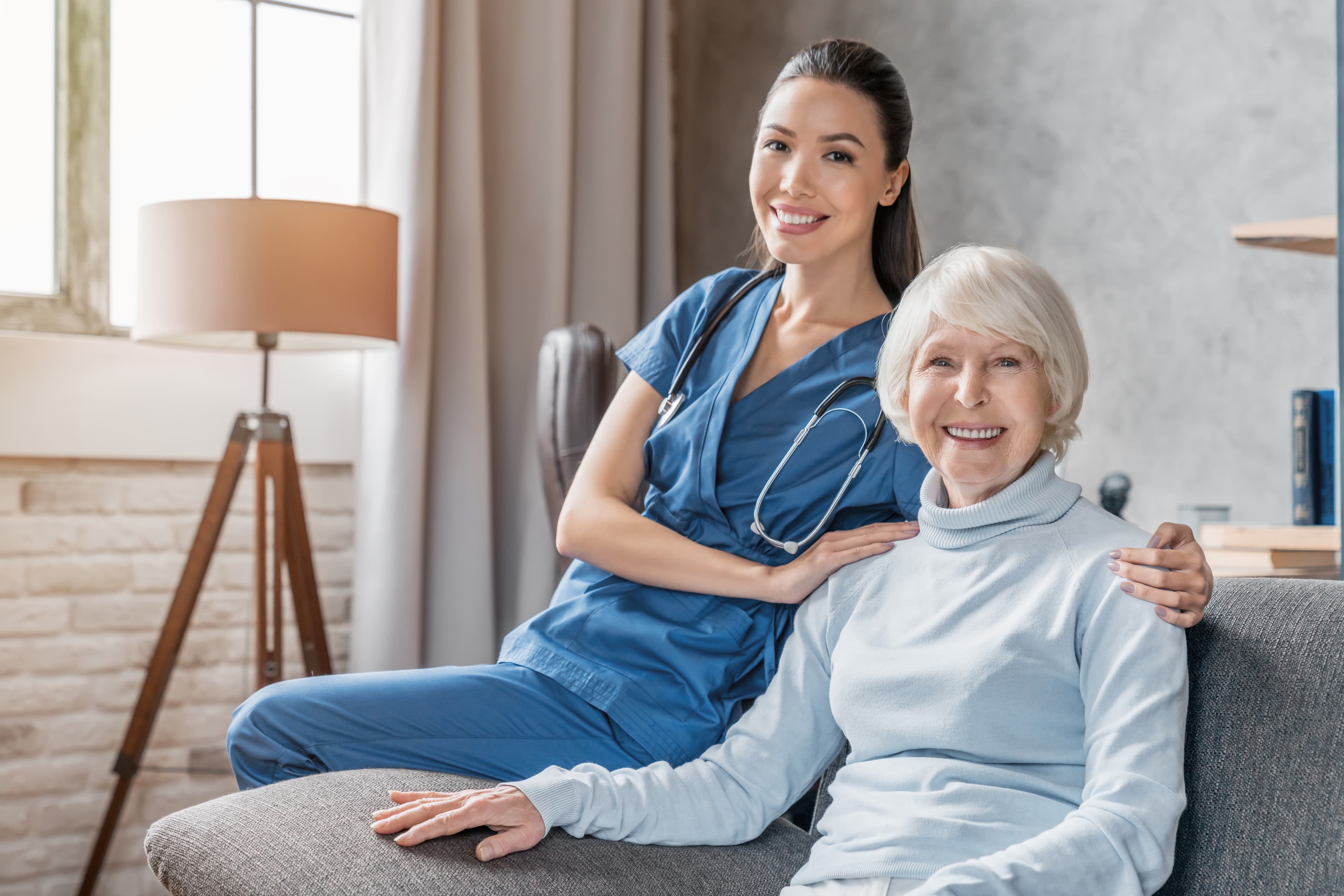 Smiling nurse and elderly woman sharing a warm moment during home care visit